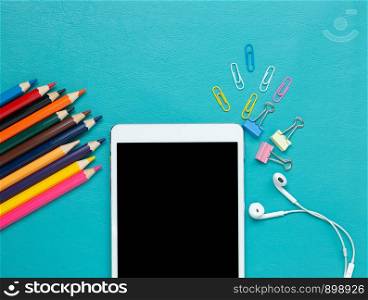 Back to School concept . School supplies and tablet on blue background.