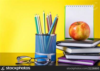Back to school concept. School supplies, apple and books on a yellow background. Place for text.. Back to school concept. School supplies and books on yellow background. Place for text.