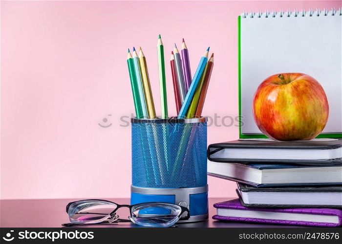 Back to school concept. School supplies, books and apple on a pink background. Place for text.. Back to school concept. School supplies, books and apple on pink background. Place for text.