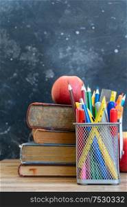 Back to school concept, school supplies with books and apples on blackboard background with copy space. back to school
