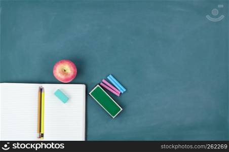 Back to school concept with writing supplies on a green chalkboard