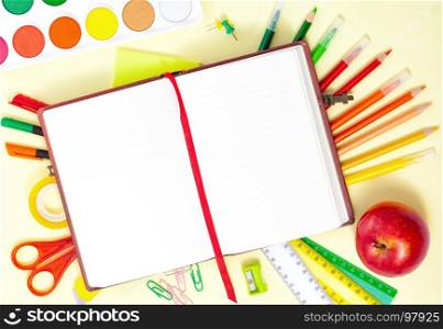 Back to School Conceptl: Empty Notebook, Colorful Pens, Pencils, Felt Pens, Red Apple, Scissors, Palette of Paint on the Yellow Background