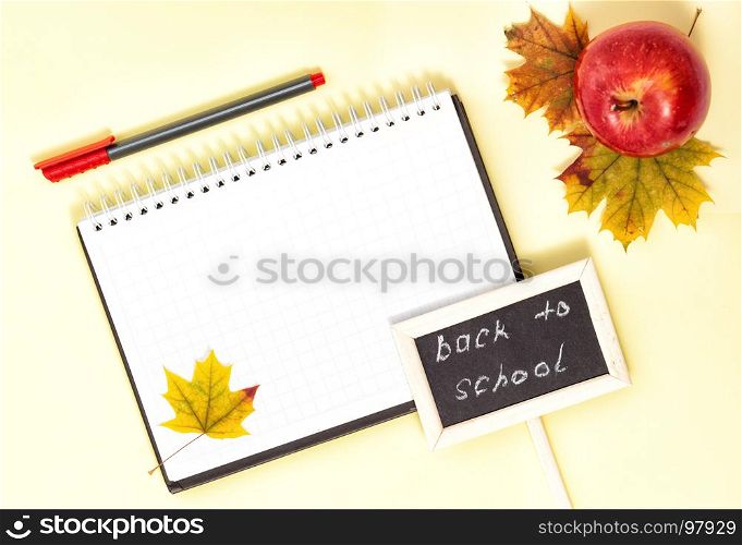 Back to School Conceptl: Red Felt Pen, Note Book, Red Apple and Mapple Leaf on the Yellow Background