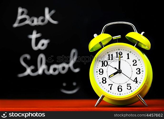 Back to school conceptual image with alarm clock &amp; chalkboard in the classroom