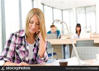 Back to school - female student in classroom writing notes