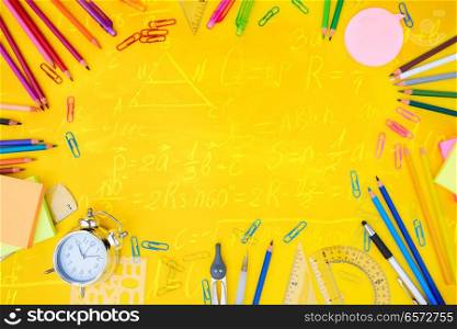 back to school or office styed scene with multicolored school supplies on yellow background with math formulas. back to school