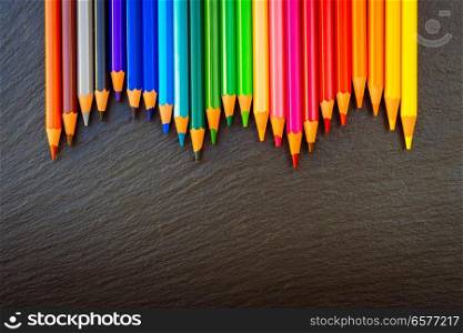 Back to school pencils color rainbow border on black board background with copy space, top view, retro toned. Back to school pencils