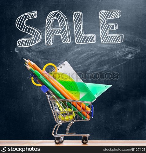 Back to school sale.. Back to school shopping cart. Accessories in trolley against chalkboard with Sale caption