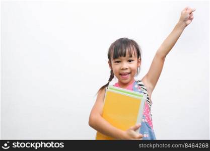 Back to school. Smiling little girl carrying a backpack holding books looking at the camera with arms raised on a white background with copy space. Girl glad ready to study.