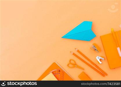 Back to school styled border with school supplies and paper blue plane orange background. back to school
