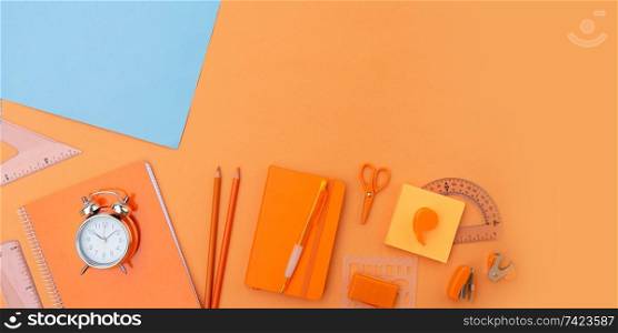 Back to school styled flat lay scene with school supplies on blue and orange background. back to school