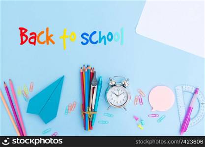 Back to school styled scene with school supplies on blue background with greeting. back to school