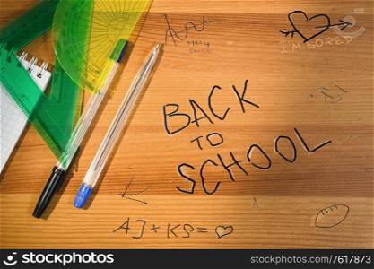 Back to school writing on wooden desk. Top view of school table with supplies and accessories. Shadow and sun beam overlay.. Back to school