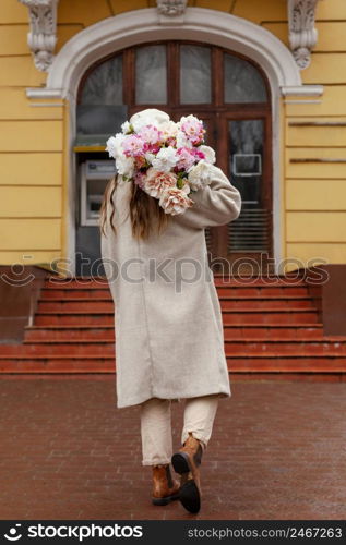 back view beautiful woman holding bouquet flowers outside