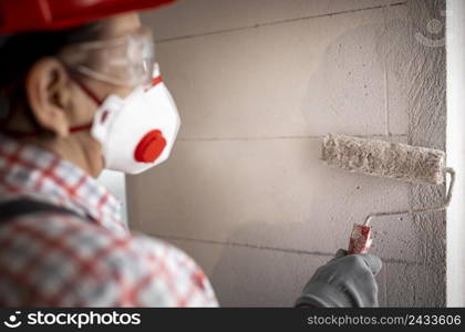 back view female construction worker with helmet paint roller