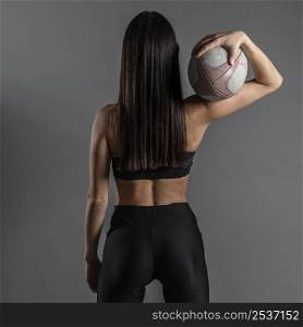 back view female rugby player posing while holding ball