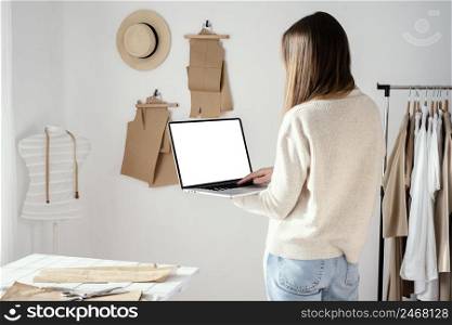 back view female tailor studio using laptop