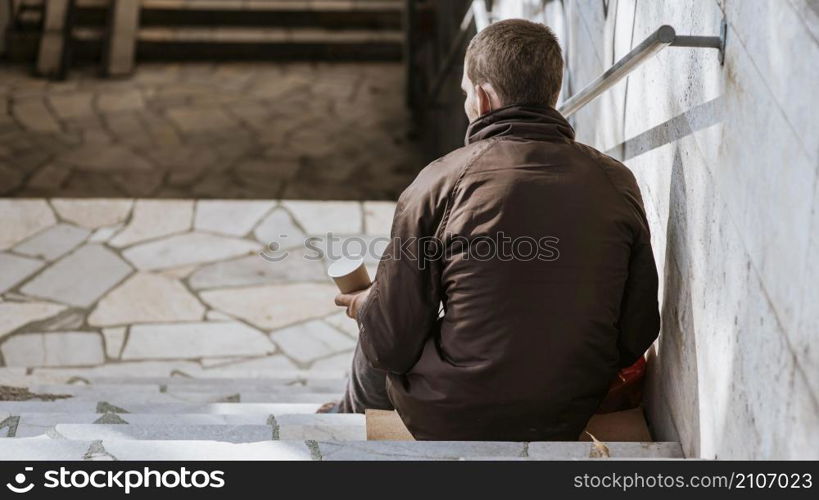 back view homeless man with cup stairs