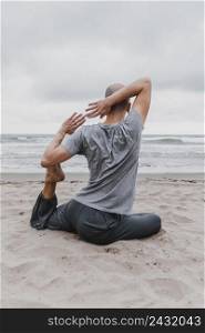back view man beach exercising yoga