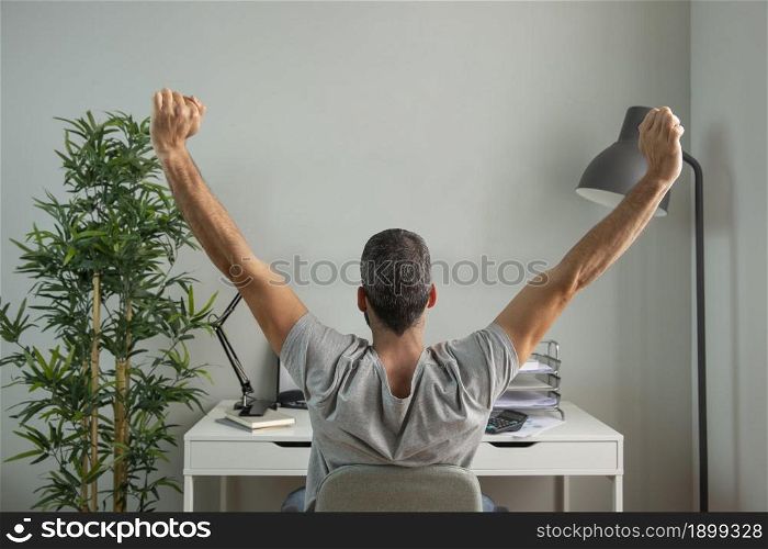 back view man stretching his arms while working from home. Resolution and high quality beautiful photo. back view man stretching his arms while working from home. High quality beautiful photo concept