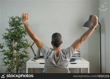 back view man stretching his arms while working from home. Resolution and high quality beautiful photo. back view man stretching his arms while working from home. High quality beautiful photo concept