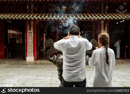 back view man woman praying temple with burning incense