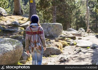 Back view of a backpacker woman wearing a wool cap hiking