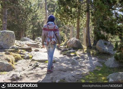 Back view of a backpacker woman wearing a wool cap hiking