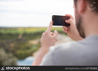 Back view of a mann taking photograph with a smart phone camera