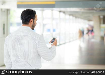 Back view of a of businessman using mobile smartphone.