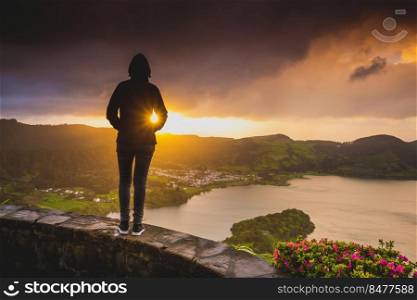 Back view of a woman looking to a beautiful sunset in Acores, Portugal