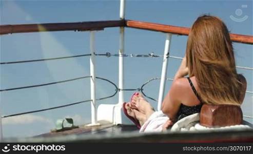 Back view of a woman relaxing alone on the deck of a yacht or ship