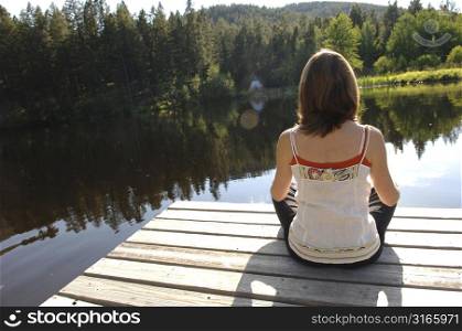 Back view of a woman sitting on a dock