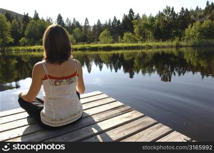 Back view of a woman sitting on a dock