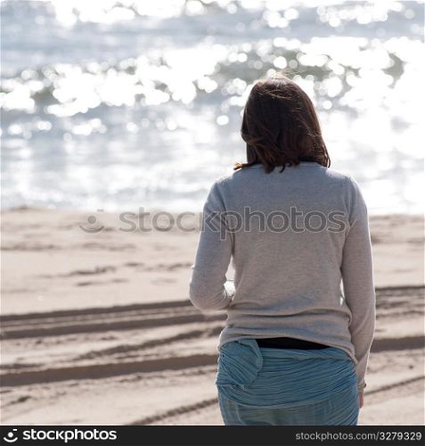 Back view of a woman walking along the beach in the Hamptons