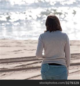 Back view of a woman walking along the beach in the Hamptons