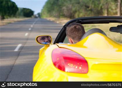 Back view of a young man driving his convertible yellow car. Open roof