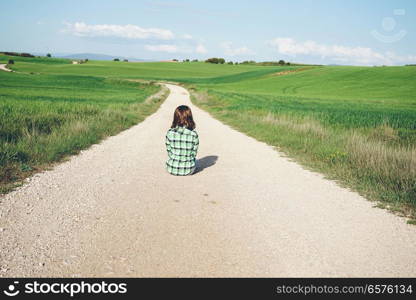 Back view of a young woman alone in a green field
