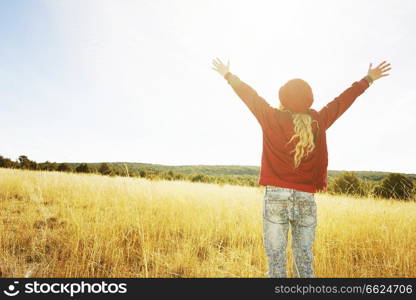 Back view of a young woman in nature in a sunny autumn day                               