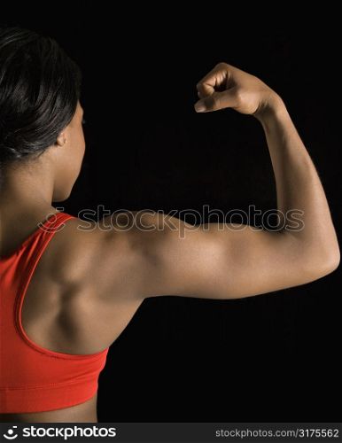 Back view of African American woman flexing muscular bicep.