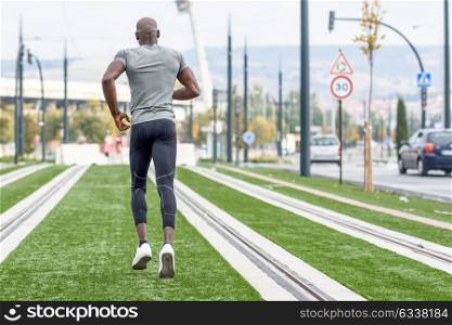 Back view of black man running in urban background. Young guy doing workout outdoors.