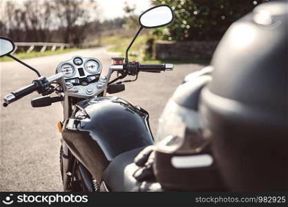 Back view of black shiny motorcycle on road over a nature background. Black motorcycle on road over nature background