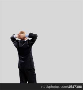 Back view of businessman. Back view image of businessman with arms crossed behind head. Place for text