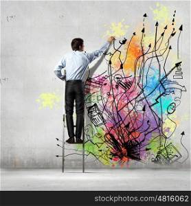 Back view of businessman. Back view of businessman drawing colorful business ideas on wall