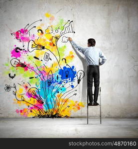Back view of businessman. Back view of businessman drawing colorful business ideas on wall