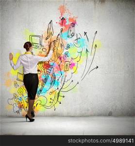Back view of businesswoman. Back view of businesswoman drawing colorful business ideas on wall