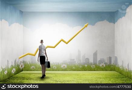 Back view of businesswoman looking at growing graph