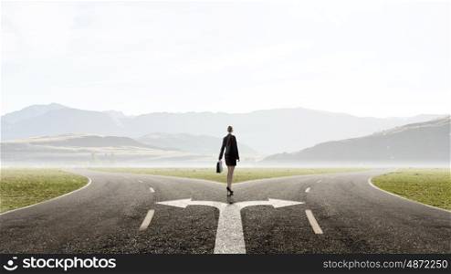 Back view of businesswoman standing on crossroads and making choice. Choose your way