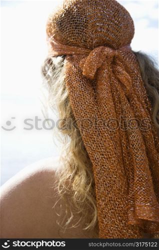 Back view of Caucasian mid-adult woman with wavy hair and head scarf.