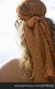 Back view of Caucasian mid-adult woman with wavy hair and head scarf.